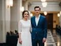 Para w eleganckich strojach, w czym do ślubu. Ona w koronkowej białej sukni, on w granatowym garniturze.