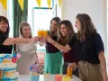 Kobiety świętują baby shower, wznosząc toasty. Widać tort z pieluch i dekoracje. Idealny strój na baby shower to coś wygodnego i eleganckiego.