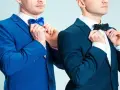 Dwóch mężczyzn w granatowych garniturach poprawia muszki. Jeden w niebieskiej, drugi w czarnej. Jaka mucha do granatowego garnituru?
