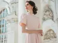 Elegancka kobieta w pudrowej sukience, idealna inspiracja, jak się ubrać na chrzciny.