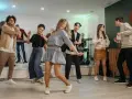 Luźne stylizacje na domówkę: jeansy, sukienka i wygodne buty. Wszyscy tańczą i świetnie się bawią.