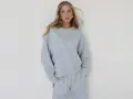 Kobieta w błękitnym, luźnym komplecie dresowym. Eleganckie dresy stylizacje, które łączą komfort z modnym wyglądem.