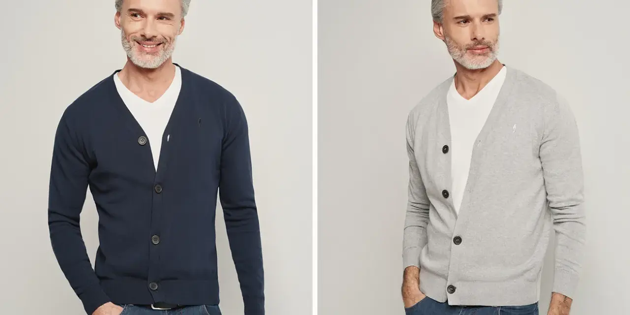 Elegancki mężczyzna pokazuje, jak nosić sweter męski: granatowy i szary kardigan z białym t-shirtem i jeansami.