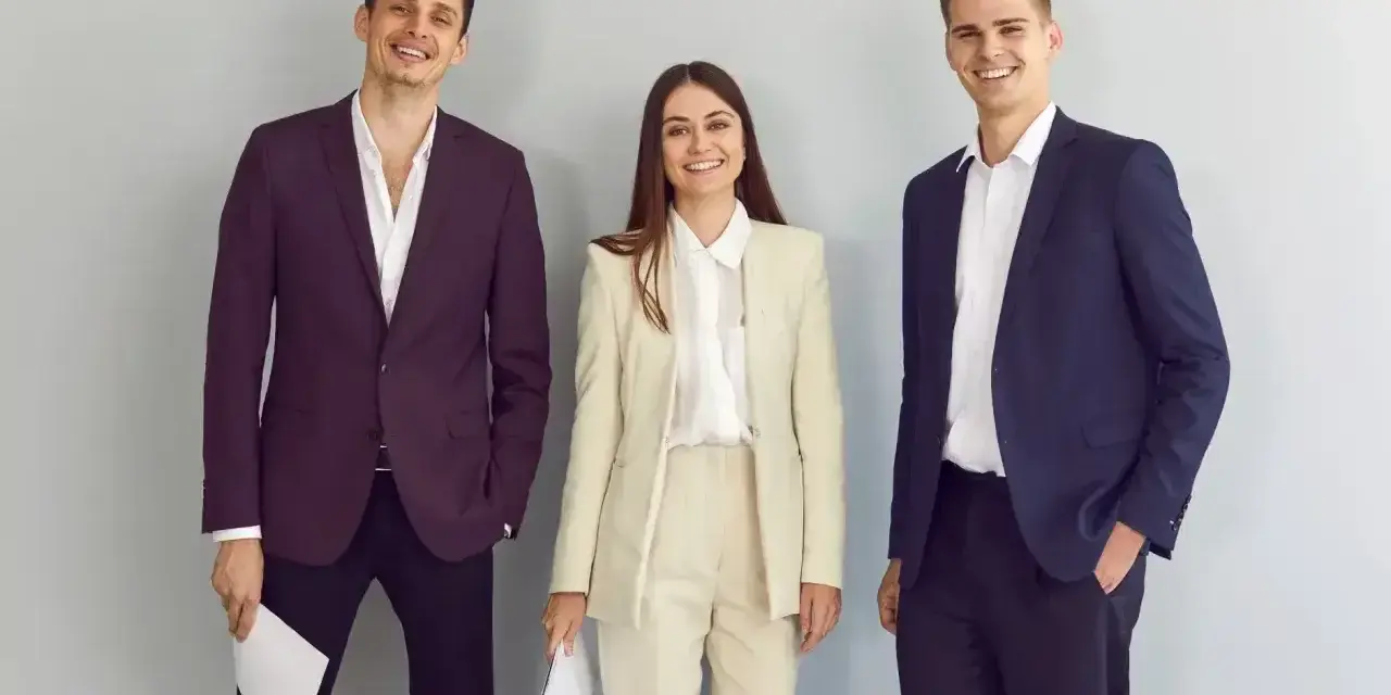 Trzy osoby w eleganckich strojach biznesowych, idealnych, by pokazać, jak się ubrać na rozmowę o pracę.