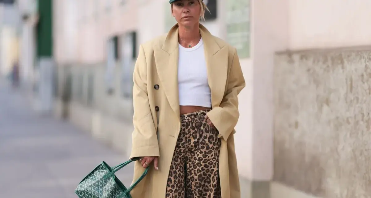 Modna kobieta w beżowym płaszczu i spodniach w panterkę. Stylowe spodnie w panterkę to klucz do odważnych stylizacji.