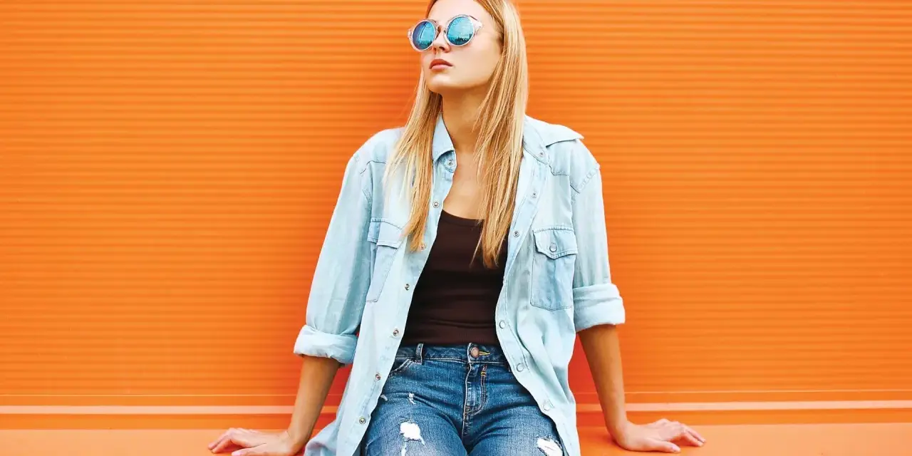 Dziewczyna w okularach i jeansach, z luźną koszulą jeansową z czym łączyć – idealny casualowy look na co dzień.