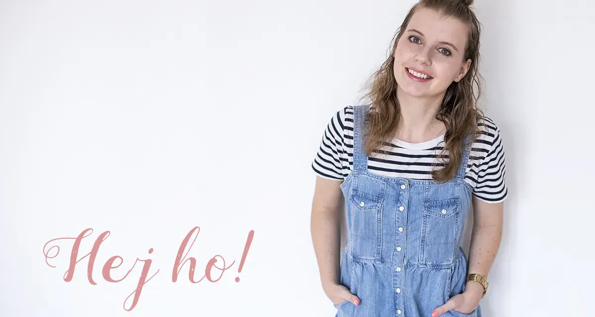 Uśmiechnięta dziewczyna w stylu normcore, w jeansowej sukience na szelkach i pasiastym t-shircie, z napisem "Hej ho!".