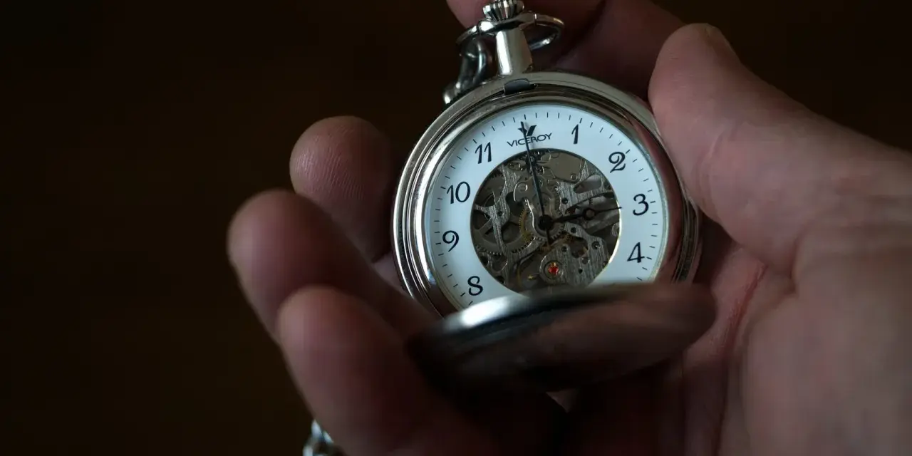 Dłoń trzyma srebrny zegarek kieszonkowy Viceroy z widocznym mechanizmem. Klasyczny sposób, jak nosić zegarek kieszonkowy.