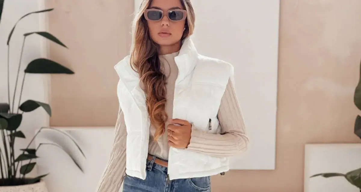 Modna kobieta w białej kamizelce i okularach przeciwsłonecznych prezentuje stylowe stylizacje z kamizelką.