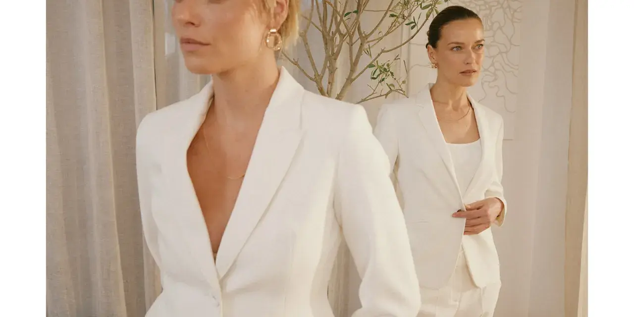 Dwie kobiety w białych garniturach, uosobienie power dressingu. Eleganckie, pewne siebie, gotowe na podbój świata.