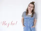 Uśmiechnięta dziewczyna w stylu normcore, w jeansowej sukience na szelkach i pasiastym t-shircie, z napisem "Hej ho!".