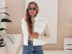 Modna kobieta w białej kamizelce i okularach przeciwsłonecznych prezentuje stylowe stylizacje z kamizelką.
