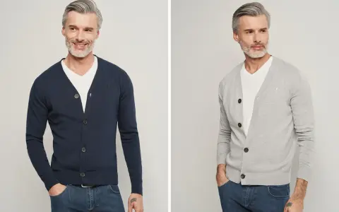Elegancki mężczyzna pokazuje, jak nosić sweter męski: granatowy i szary kardigan z białym t-shirtem i jeansami.