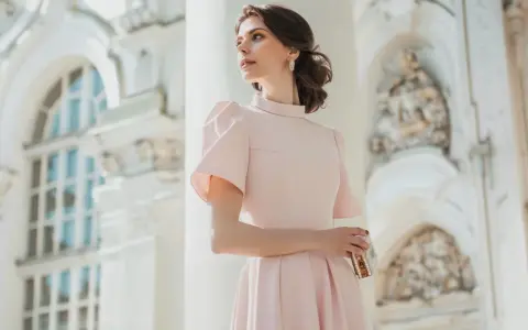 Elegancka kobieta w pudrowej sukience, idealna inspiracja, jak się ubrać na chrzciny.