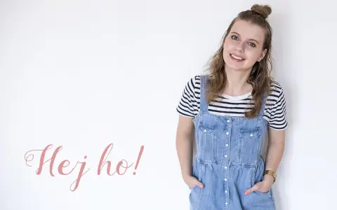 Uśmiechnięta dziewczyna w stylu normcore, w jeansowej sukience na szelkach i pasiastym t-shircie, z napisem "Hej ho!".