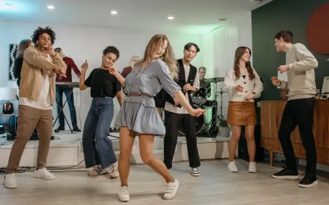 Luźne stylizacje na domówkę: jeansy, sukienka i wygodne buty. Wszyscy tańczą i świetnie się bawią.