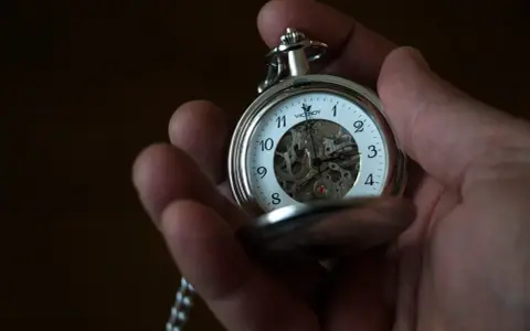 Dłoń trzyma srebrny zegarek kieszonkowy Viceroy z widocznym mechanizmem. Klasyczny sposób, jak nosić zegarek kieszonkowy.