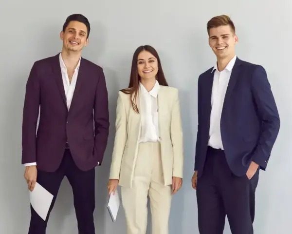 Trzy osoby w eleganckich strojach biznesowych, idealnych, by pokazać, jak się ubrać na rozmowę o pracę.