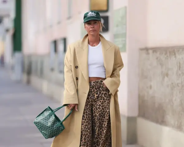 Modna kobieta w beżowym płaszczu i spodniach w panterkę. Stylowe spodnie w panterkę to klucz do odważnych stylizacji.