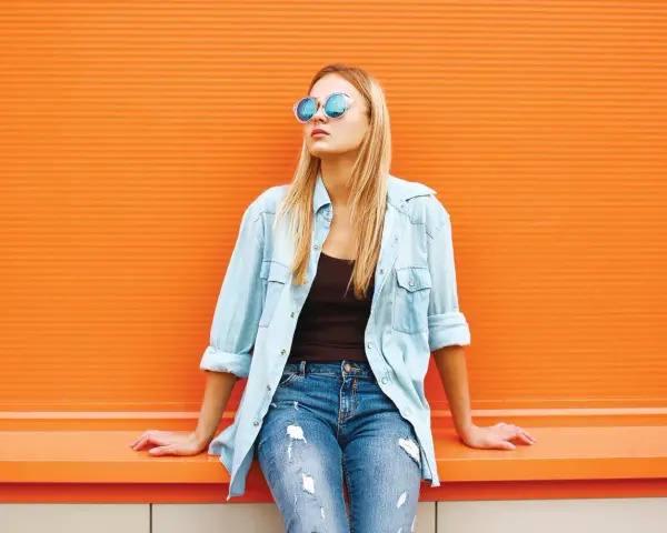 Dziewczyna w okularach i jeansach, z luźną koszulą jeansową z czym łączyć – idealny casualowy look na co dzień.