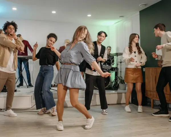 Luźne stylizacje na domówkę: jeansy, sukienka i wygodne buty. Wszyscy tańczą i świetnie się bawią.