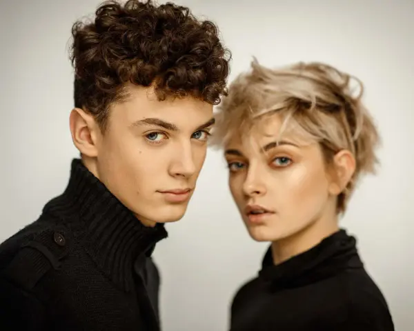Młoda para, on z kręconymi włosami, ona z blond pixie cut, w czarnych golfach. Ich spojrzenia sugerują, że tworzą idealny **matching** duet.