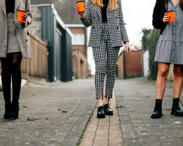 Trzy kobiety w kratę. Jakie buty do spodni w kratę męskie? Eleganckie oksfordki, botki lub sznurowane trapery.