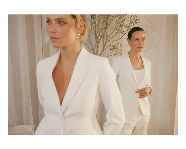 Dwie kobiety w białych garniturach, uosobienie power dressingu. Eleganckie, pewne siebie, gotowe na podbój świata.
