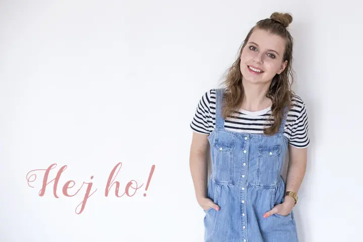 Uśmiechnięta dziewczyna w stylu normcore, w jeansowej sukience na szelkach i pasiastym t-shircie, z napisem "Hej ho!".