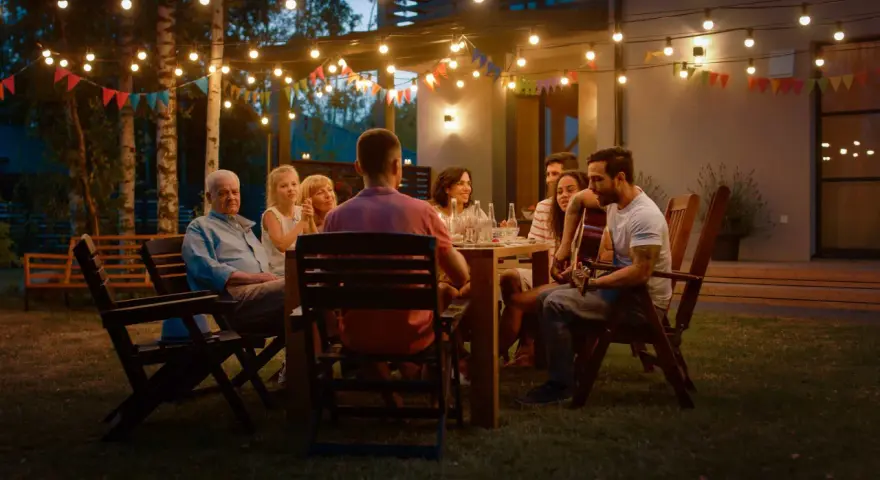 Rodzina i przyjaciele na garden party, gra na gitarze, rozmowy. Jak się ubrać? Luźne, letnie stroje idealne na wieczorne spotkanie w ogrodzie.