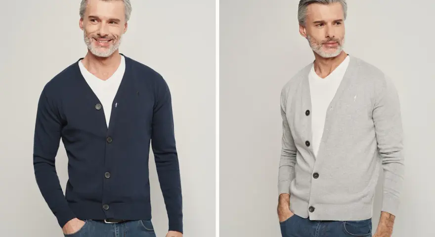 Elegancki mężczyzna pokazuje, jak nosić sweter męski: granatowy i szary kardigan z białym t-shirtem i jeansami.