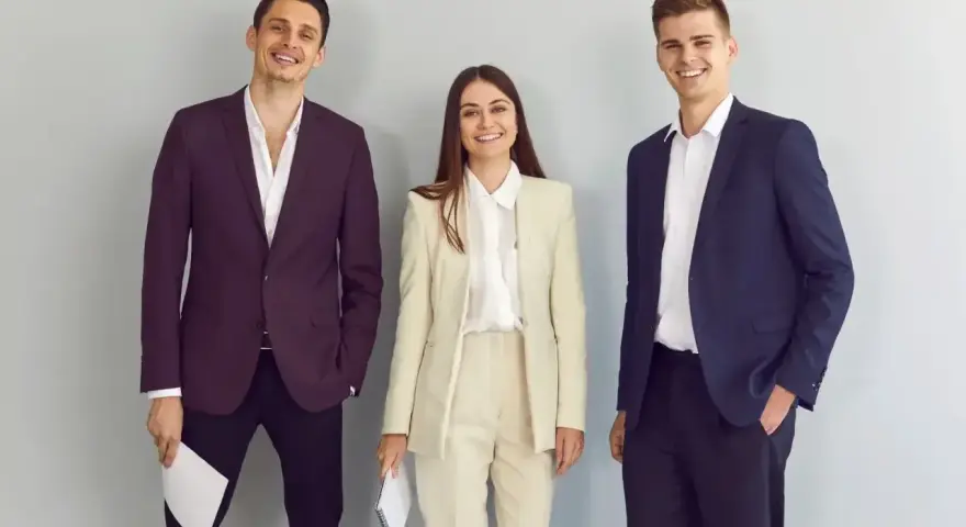 Trzy osoby w eleganckich strojach biznesowych, idealnych, by pokazać, jak się ubrać na rozmowę o pracę.