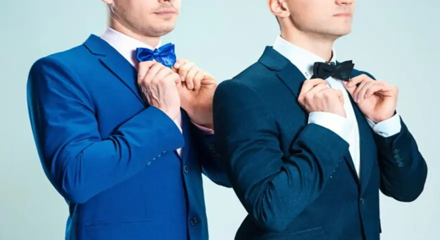 Dwóch mężczyzn w granatowych garniturach poprawia muszki. Jeden w niebieskiej, drugi w czarnej. Jaka mucha do granatowego garnituru?