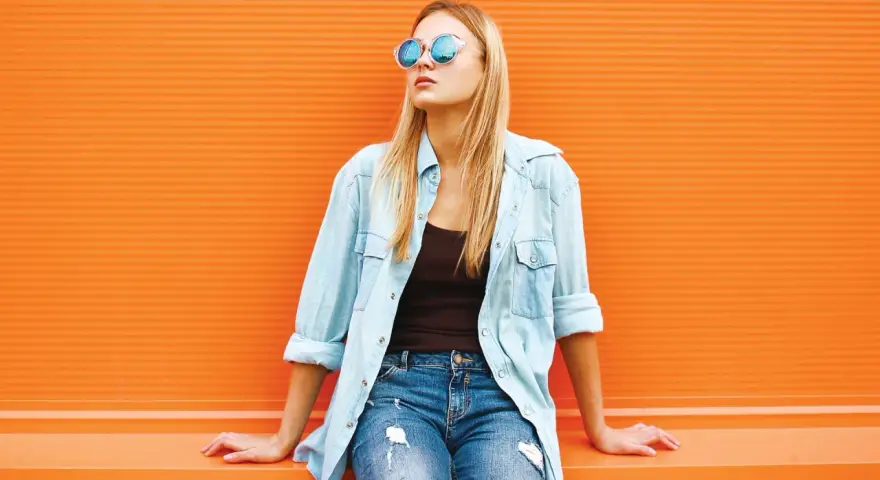 Dziewczyna w okularach i jeansach, z luźną koszulą jeansową z czym łączyć – idealny casualowy look na co dzień.
