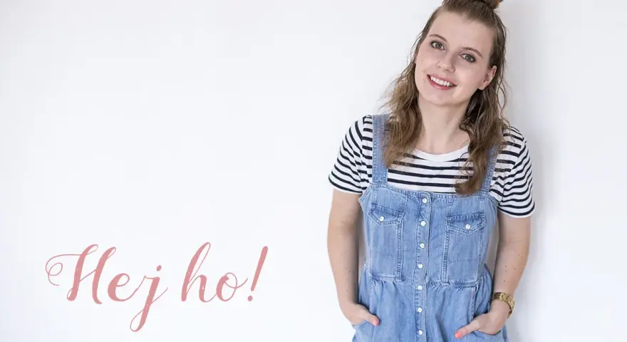 Uśmiechnięta dziewczyna w stylu normcore, w jeansowej sukience na szelkach i pasiastym t-shircie, z napisem "Hej ho!".