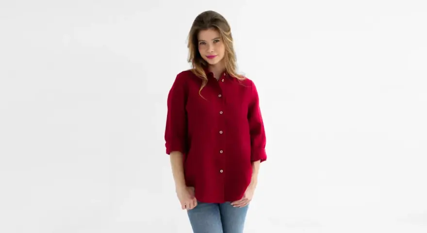Kobieta w bordowej koszuli męskiej i jeansach. Stylowa, luźna koszula to świetna baza do wielu stylizacji.