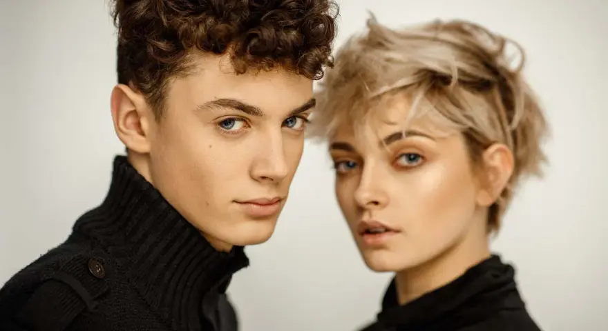 Młoda para, on z kręconymi włosami, ona z blond pixie cut, w czarnych golfach. Ich spojrzenia sugerują, że tworzą idealny **matching** duet.