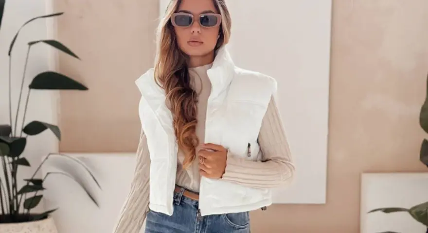 Modna kobieta w białej kamizelce i okularach przeciwsłonecznych prezentuje stylowe stylizacje z kamizelką.
