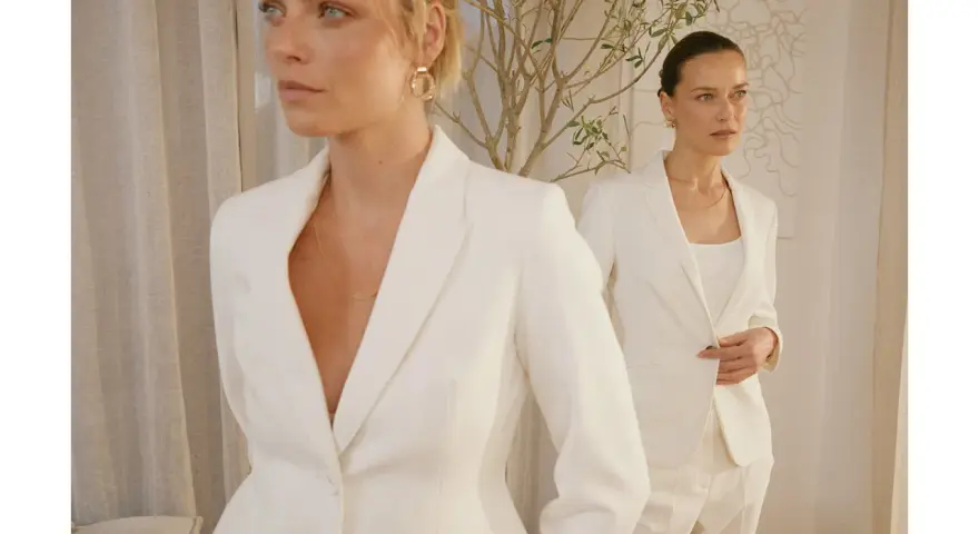 Dwie kobiety w białych garniturach, uosobienie power dressingu. Eleganckie, pewne siebie, gotowe na podbój świata.