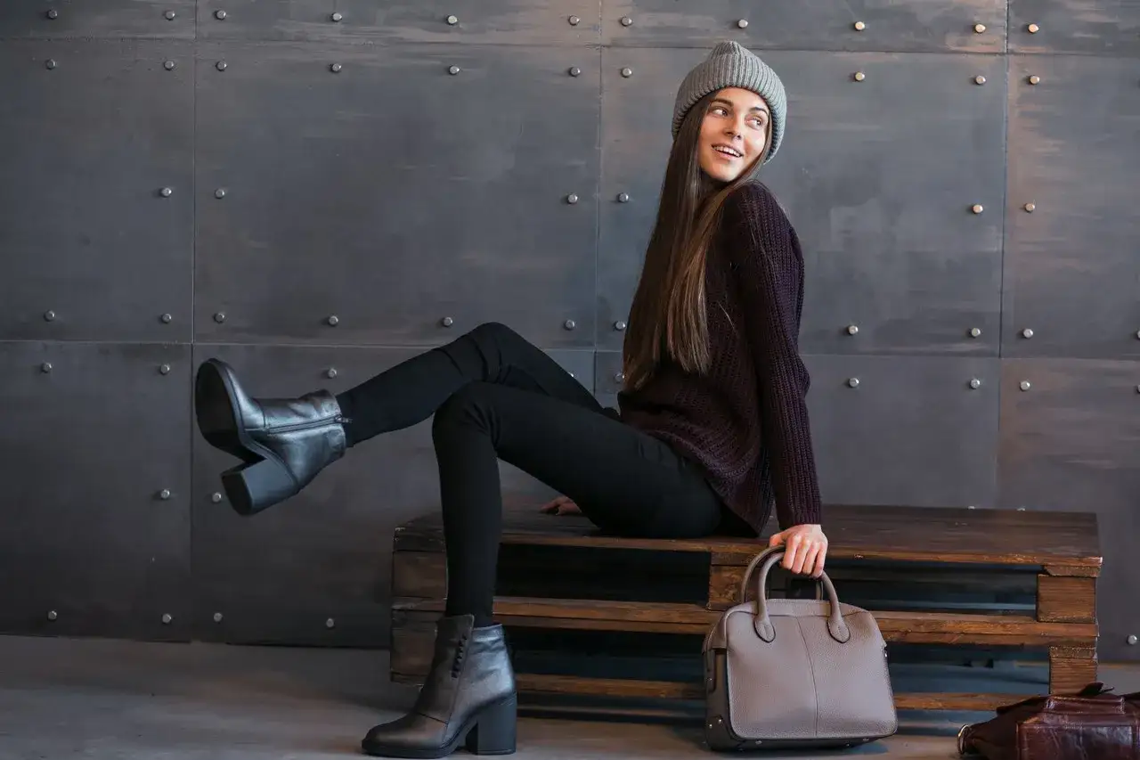Czarne, dopasowane spodnie to idealna odpowiedź na pytanie, jakie spodnie do sztyblet&oacute;w damskich. Modelka prezentuje stylowy, zimowy look.